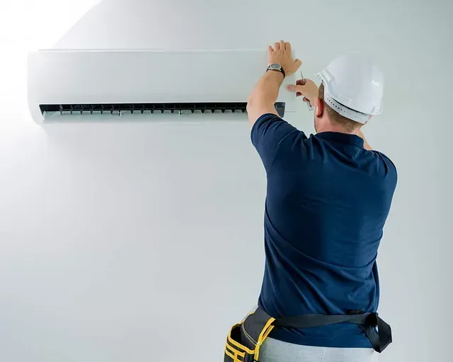 T&eacute;cnico instalando un aire acondicionado mural en una pared blanca.